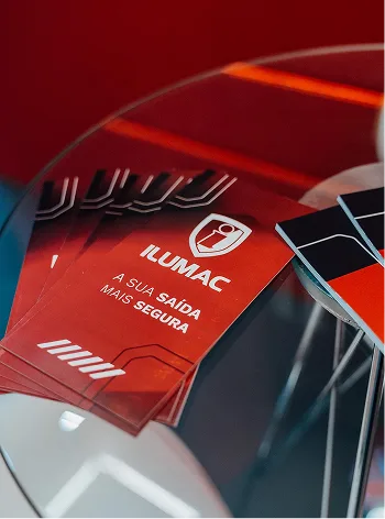 Pilha de folhetos vermelhos com a assinatura “A sua saída mais segura” sobre uma mesa de vidro